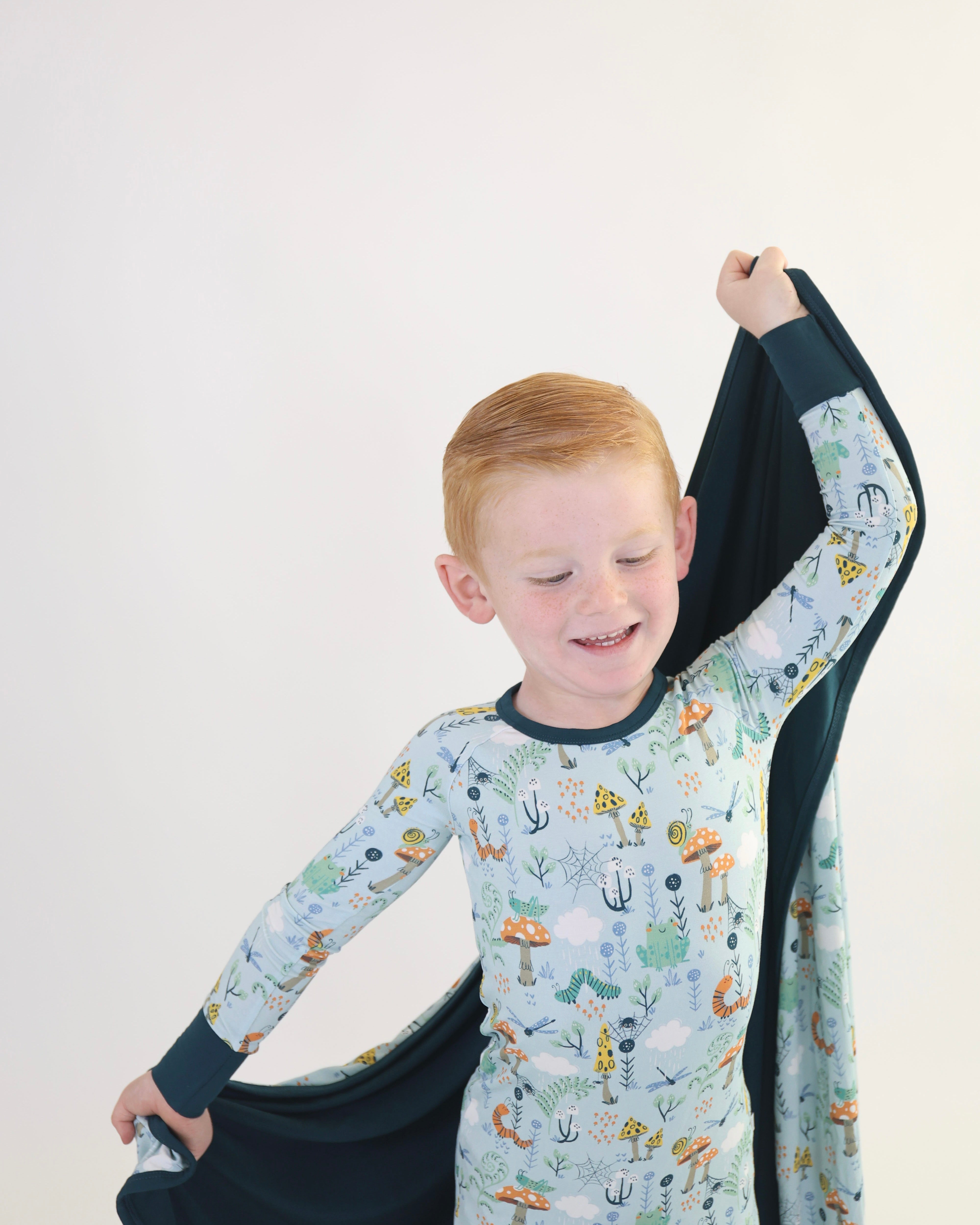 Happy child in playful pajamas, enjoying the cozy feel of a soft blanket for snuggles and cuddles.