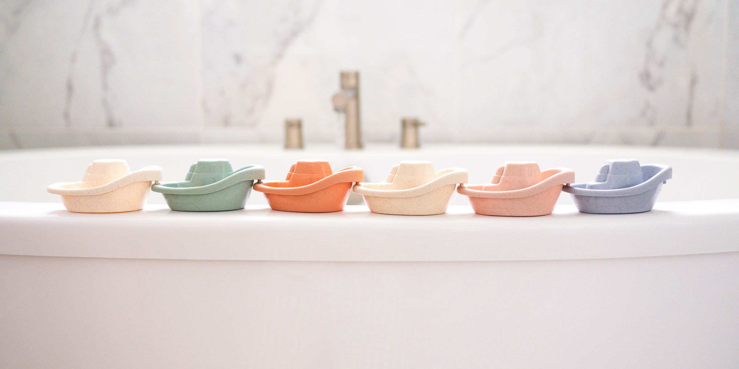 Colorful wheat straw boats from Bug + Bean Kids set on a bathtub edge, showcasing eco-friendly fun for bathtime and imaginative play.