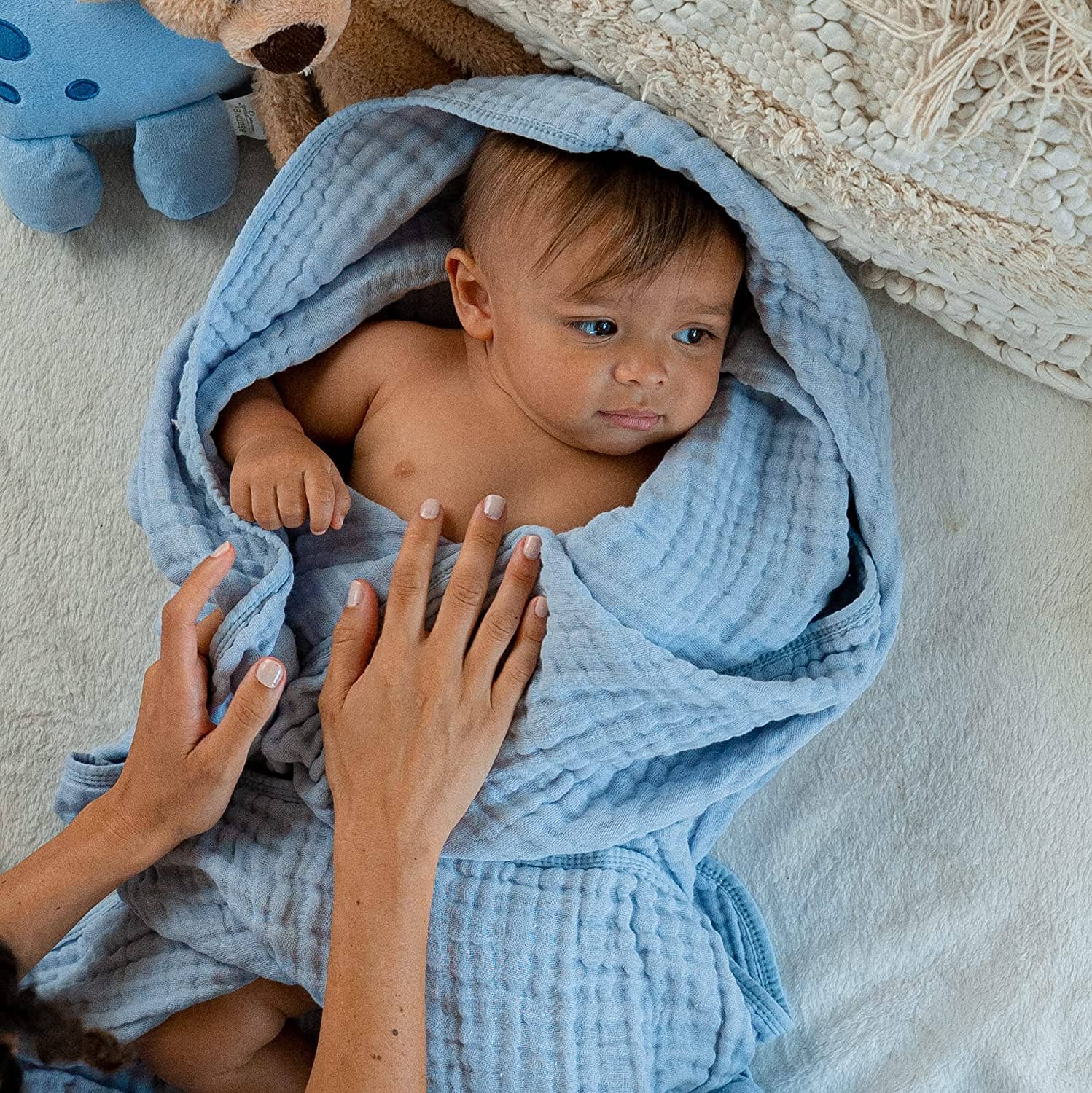 Baby wrapped in soft blue muslin cotton blanket, showcasing gentle comfort and breathability by Comfy-Cubs.