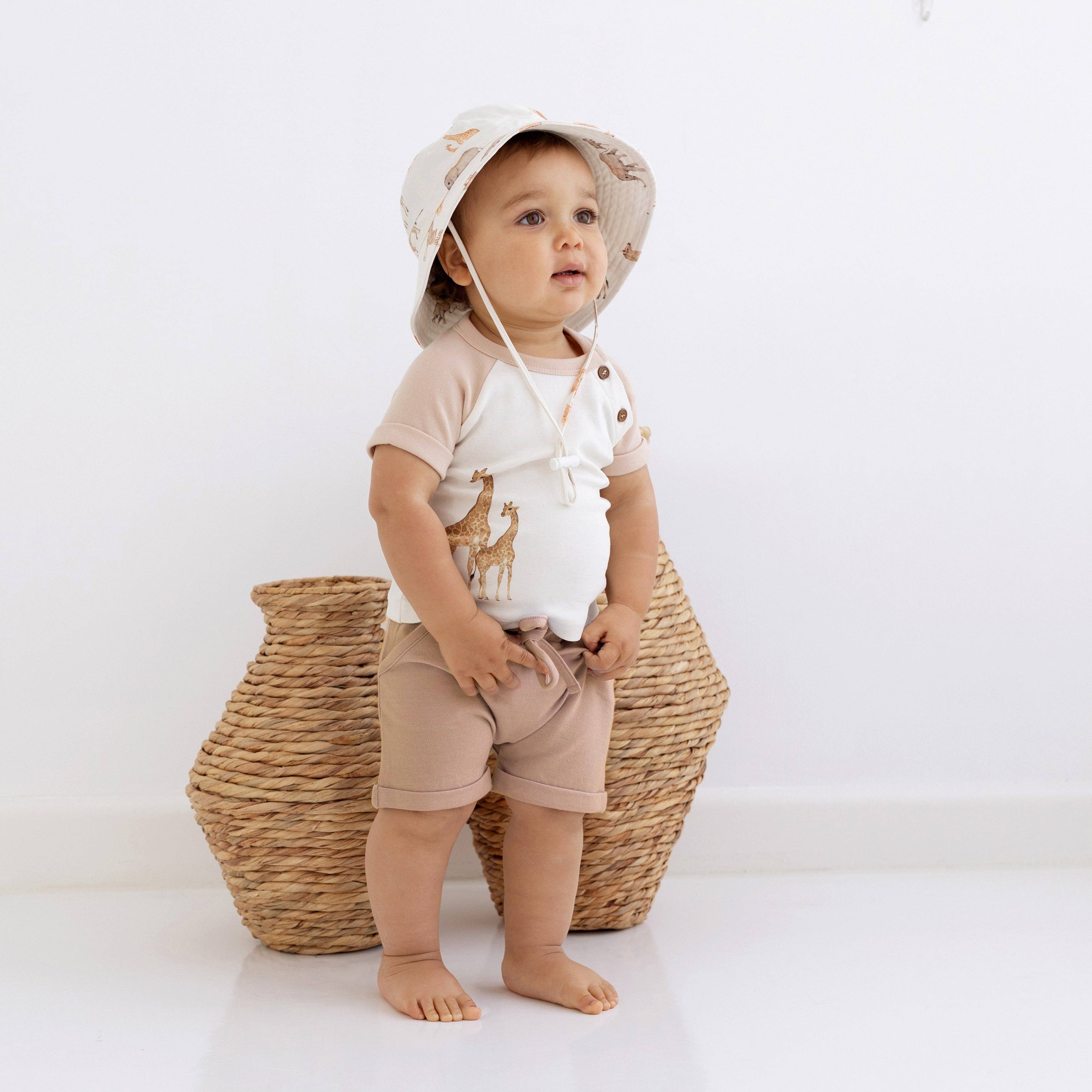 Toddler in Aster & Oak Savanna Giraffe Print Tee and shorts, ready for fun in stylish natural outfit.