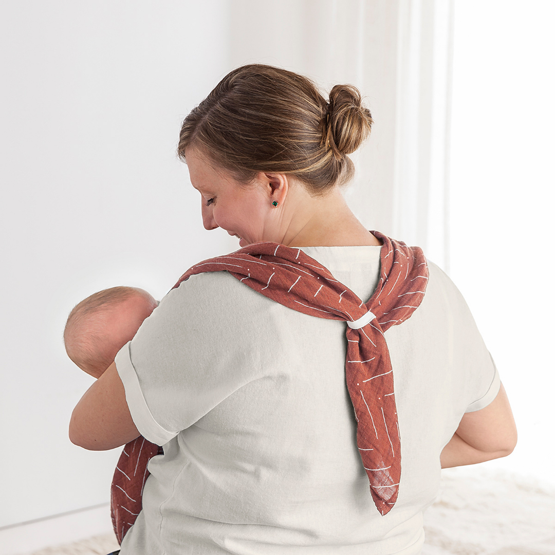 Mom using Itzy Ritzy Breastfeeding Boss™ multitasking cover for nursing and baby swaddle, showcasing comfort and style.