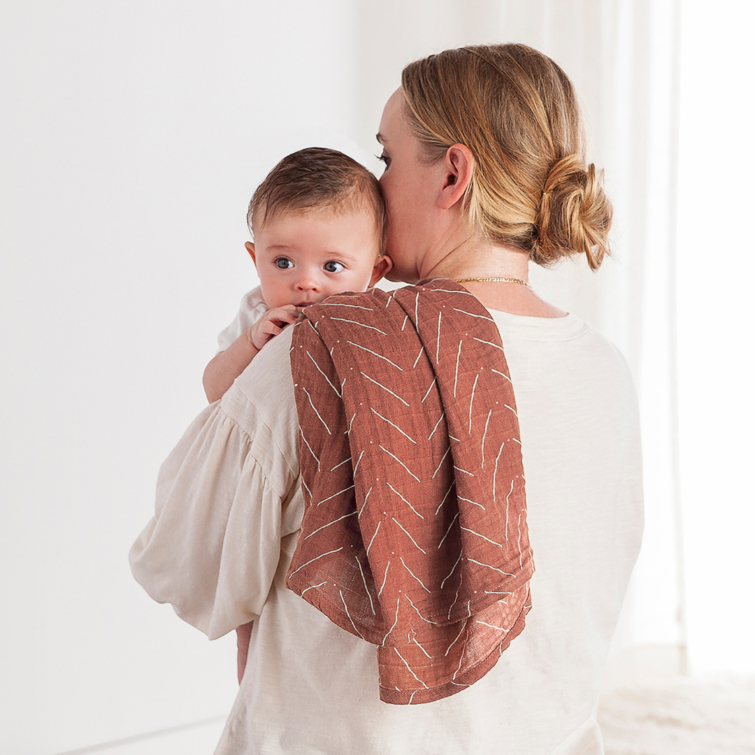 Mom holding her baby while using the Itzy Ritzy Breastfeeding Boss™ nursing cover for comfort and support.