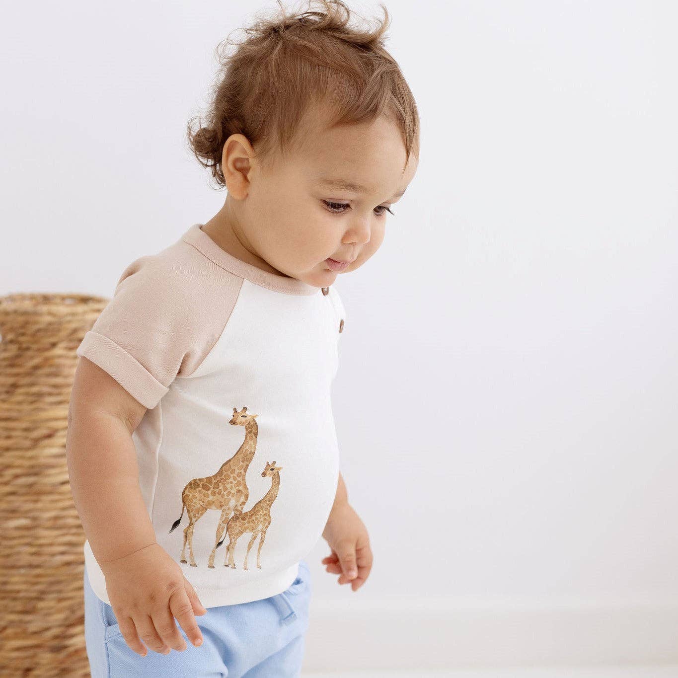 Baby wearing Aster & Oak Savanna Giraffe Print Tee in Natural, featuring playful giraffe design and raglan sleeves.