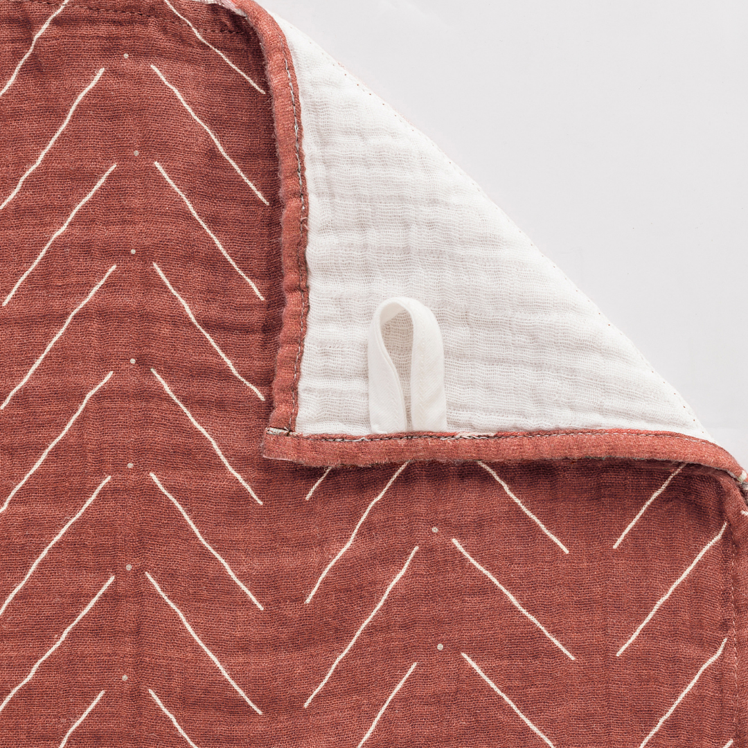 Close-up of Itzy Ritzy Breastfeeding Boss™ multi-use cotton muslin nursing cover and swaddle in earthy tones.
