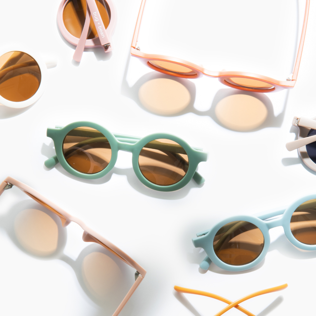 Various styles of Bug + Bean Kids recycled plastic sunglasses, including thyme green pair, showcasing sustainable and stylish eyewear options.
