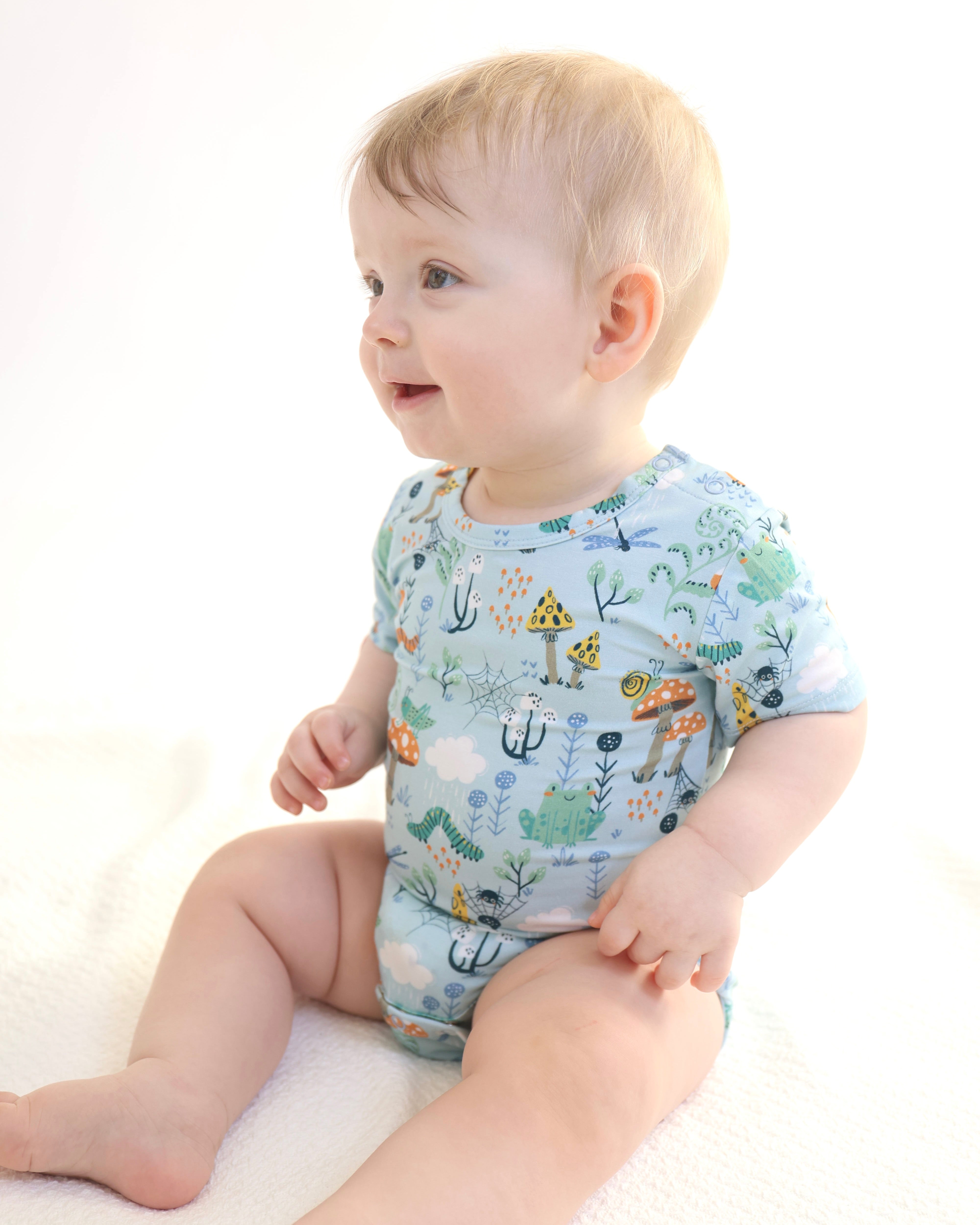 Baby in colorful Critter Hollow onesie, enjoying playful moments in soft, breathable fabric.