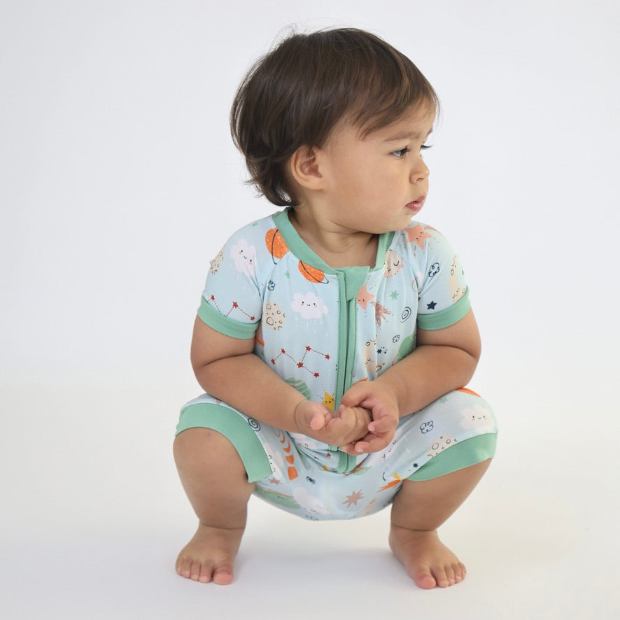 Cute child in Cosmic Short Zipp Romper by Rainn, featuring playful print and soft bamboo fabric.