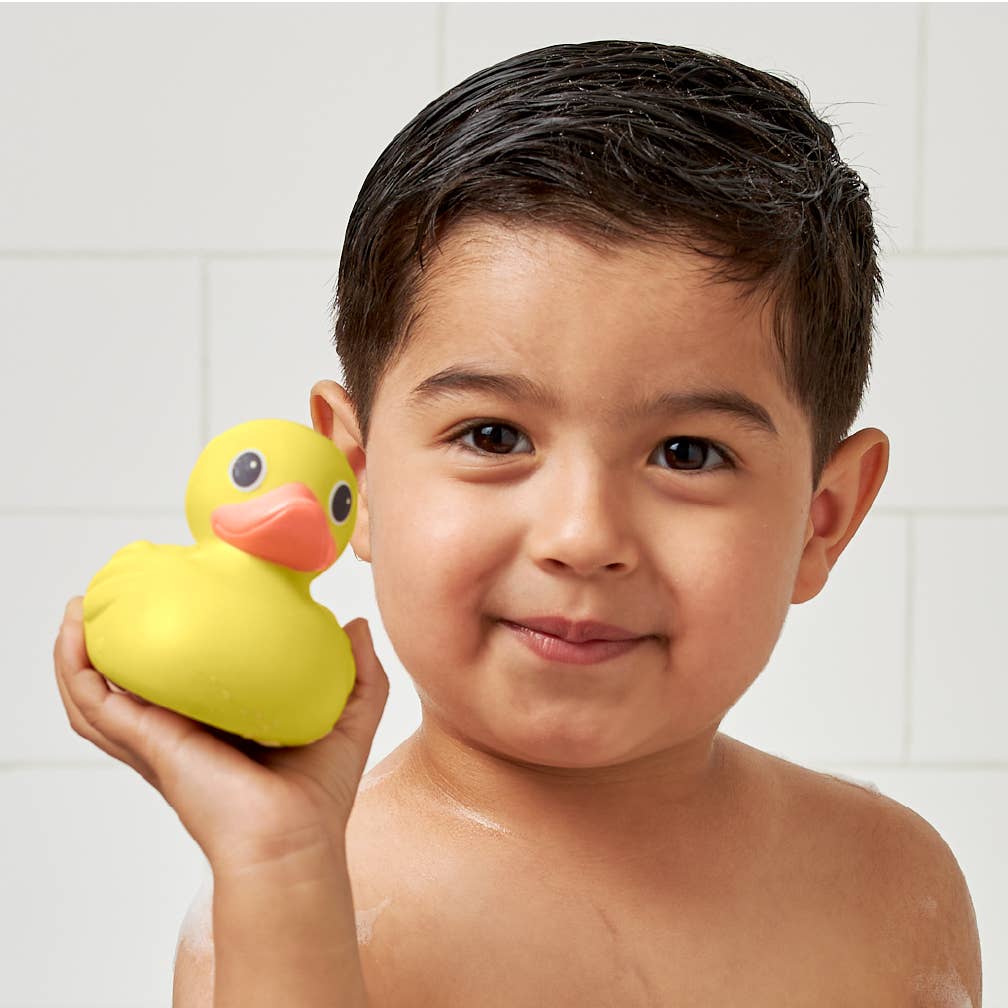 Happy boy holding a yellow rubber duck, ready for fun bath time adventures with Itzy Splash Gift Set™.