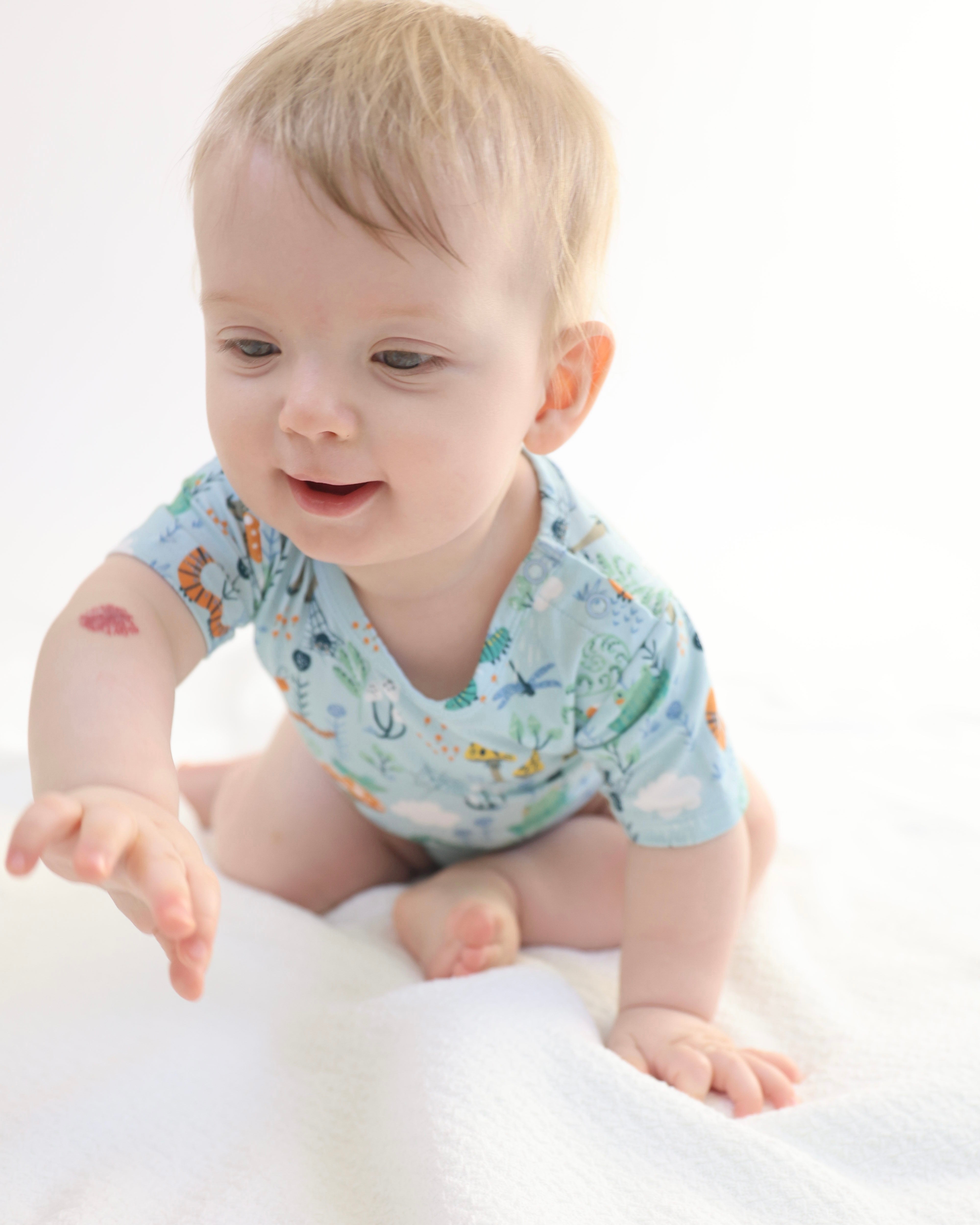 Baby in soft, breathable onesie exploring with joy, showcasing comfort and playfulness.