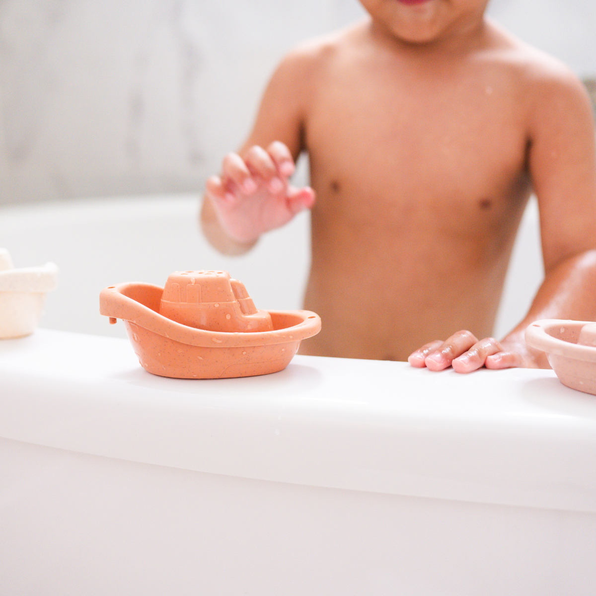 Child playing with eco-friendly Bug + Bean Kids Wheat Straw Boat Set during bath time, enjoying sustainable floating fun.