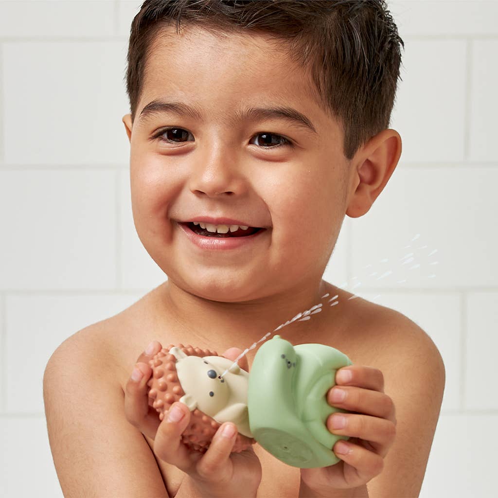 Cheerful boy playing with Itzy Squirt™ soft bath toys, squeezing characters for fun bath time adventures.