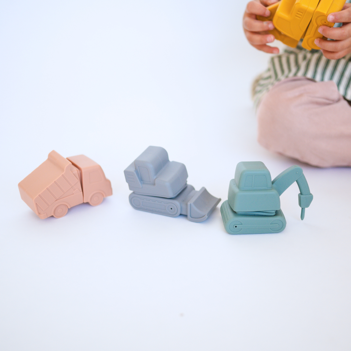 Child playing with eco-friendly silicone bath toys shaped like construction vehicles from Bug + Bean Kids.