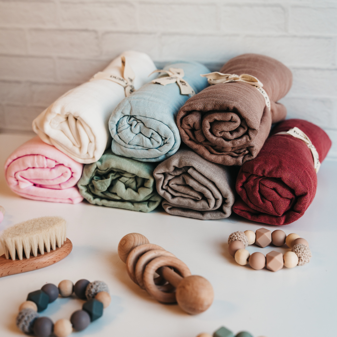Colorful bamboo muslin baby swaddles by Giften Market on a table, showcasing eco-friendly and soft newborn wraps.