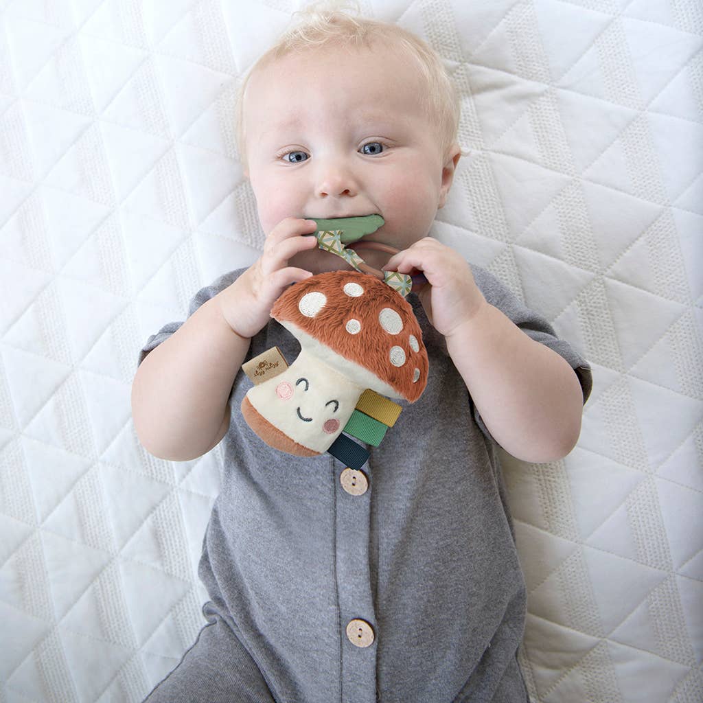 Baby enjoying Itzy Pal™ plush mushroom teether, features soft fabric and silicone to soothe sore gums, perfect for little hands.