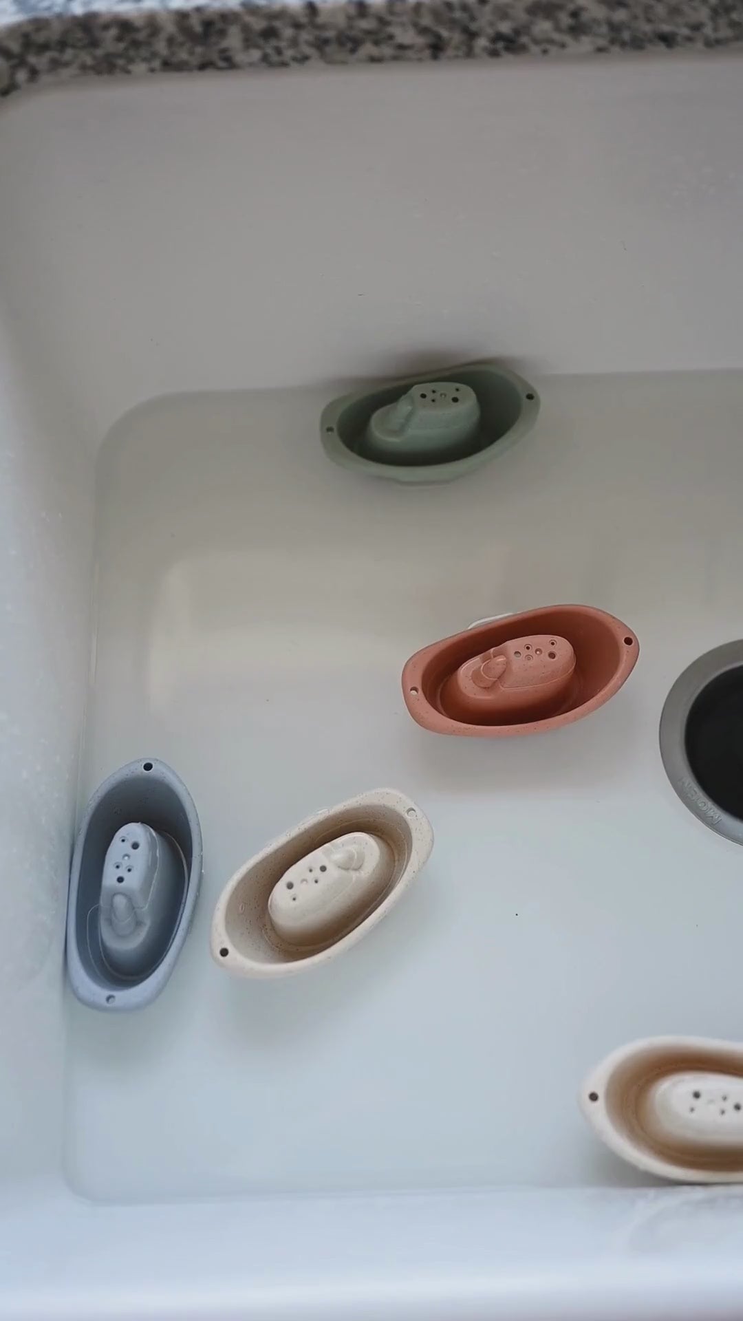 Colorful floating bath toys in a sink, showcasing eco-friendly design by bug + bean kids, perfect for imaginative water play.