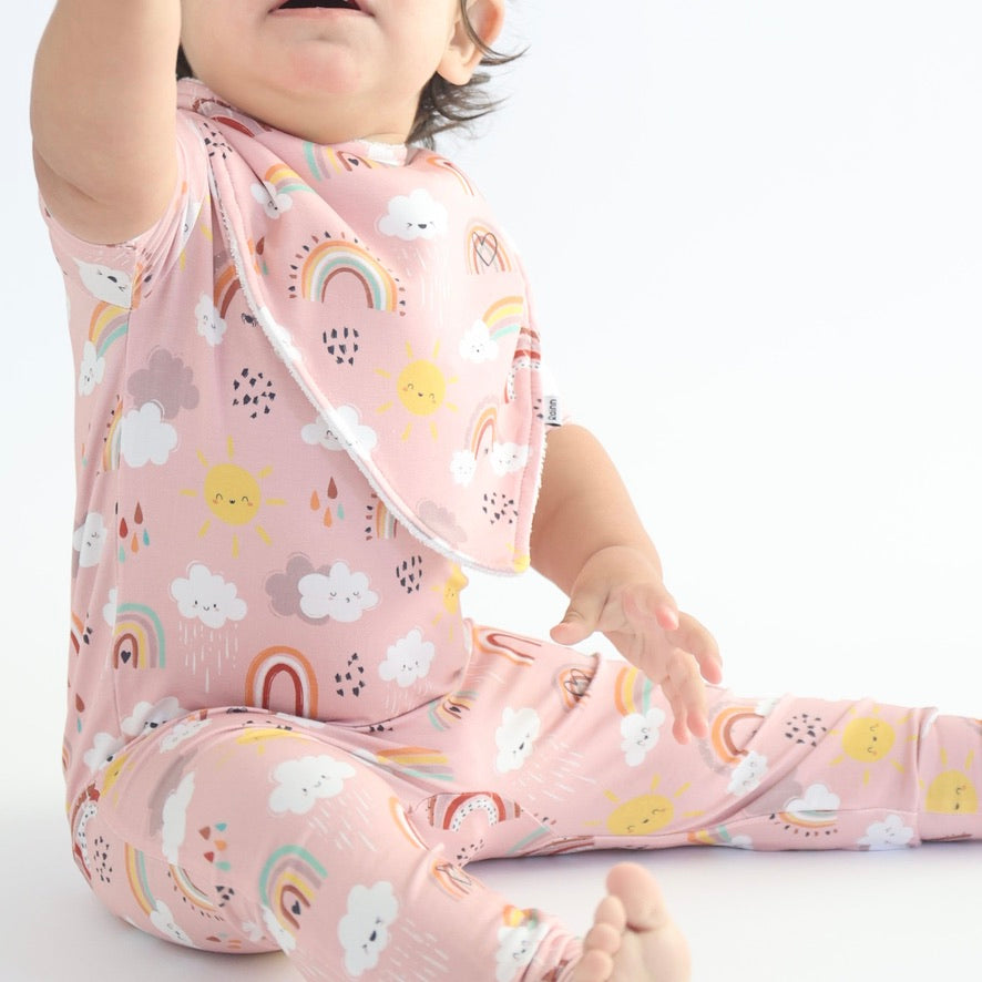 Adorable baby wearing a pink Rainnbow bandana dribble bib with colorful clouds and rainbows, perfect for drool protection.